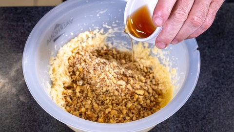 In einer Schüssel wird Marzipan und gehackte Walnuss mit Rum vermischt. Das gibt die Füllung für den Hefekranz.