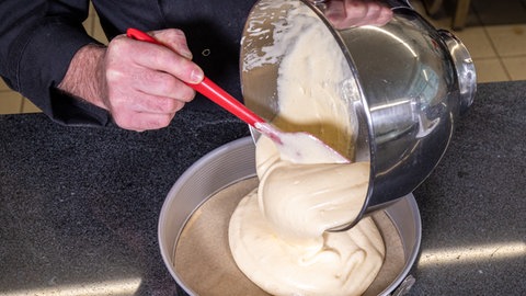 Die  Biskuitmasse für die Erdbeertorte in die mit Backpapier ausgelegte Form mit eingefetteten Rand geben. 