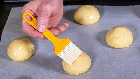 Die einzelnen Kugel aus Hefeteig werden mit der Eistreiche bestrichen. Danach einfach jede Osterpinzedie über Kreuz tief einschneiden, das gibt dem traditionellen Gebäck zu Ostern aus Österreich die typische Form.