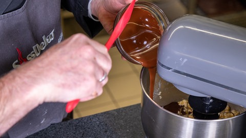 Geschmolzene Schokolade wird in eine Küchenmaschine gegeben.