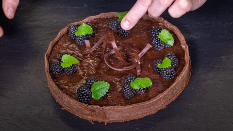 Brombeeren, Minzblätter und Schokosplitter machen aus dem leckeren Schokokuchen einen Hingucker.