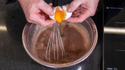 Das Ei zum Schluss stabilisiert die Creme für den Schokokuchen.