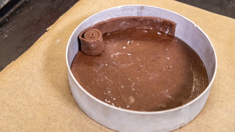 Für den Rand des Schokokuchens rollen sie einfach Mürbeteig-Streifen auf und kleiden damit den Backring aus.