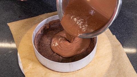 Die vorbereitete Schokocreme für den Schokokuchen kommt in den Boden aus vorgebackenen Mürbeteig.