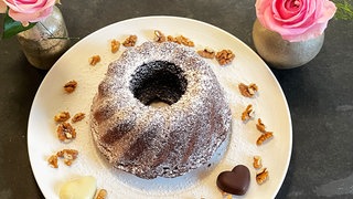 Kuchen in Gugelhupfform auf einem Teller, dekoriert mit Walnüssen