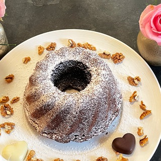 Kuchen in Gugelhupfform auf einem Teller, dekoriert mit Walnüssen