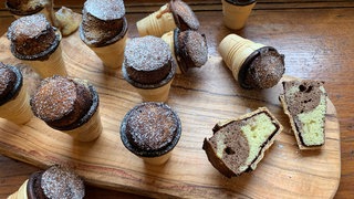 Auf einem Tisch liegen viele kleine Kuchen im Waffelbecher. Das ideale Rezept, um schnell kleine Marmorkuchen für die nächste Party, den Kindergeburtstag oder als Snack für die Schule zu backen.