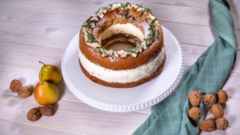 Ein fertiger Walnuss-Birnen-Kranz auf einer Tortenplatte.