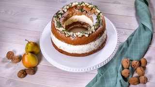 Ein fertiger Walnuss-Birnen-Kranz auf einer Tortenplatte.