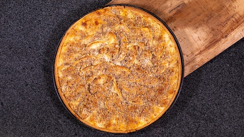 Rezept für Apfelwähe: Der Apfelkuchen liegt nach dem Backen zum Auskühlen auf einem Holzbrett.