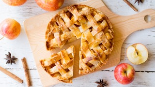 Apfelkuchen mit verschiedenen Äpfeln daneben