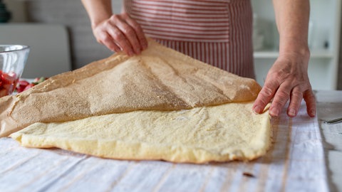 Frau entfernt vom Biskuitboden das Backpapier