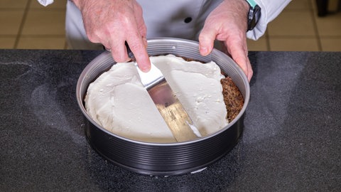 Der Zwischenboden der Eierlikörtorte wird mit Sahne bestrichen.