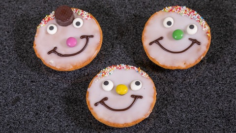 Die selbst gebackenen Amerikaner liegen bunt verzierte auf einer Arbeitsplatte.