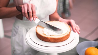 Frau bestreicht Tortenboden
