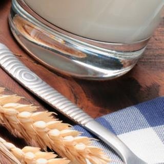 Ein Frühstückstisch mit einer Schale Müsli mit Obst, einem Glas Milch, und Brot.