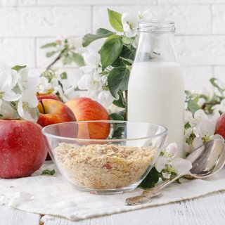Müsli in Schüssel, daneben liegen Äpfel