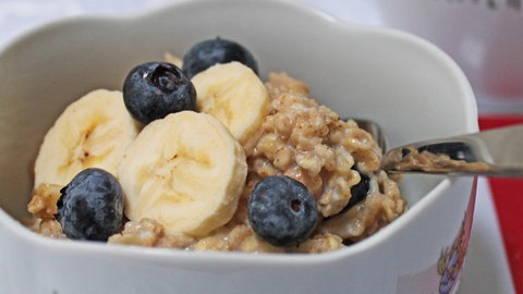 Porridge mit Banane und Blaubeeren in einer Müslischüssel mit Blumenmuster