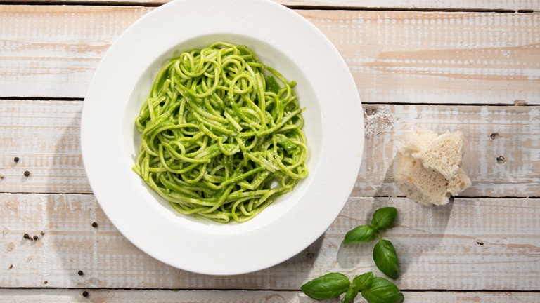 Grünes Pesto auf Spaghetti in einem Teller angerichtet.