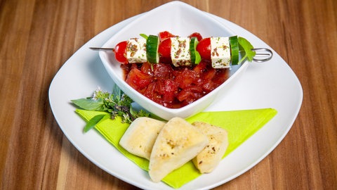 Marinierte Tomatenwürfel mit Fetaspießen auf einem Teller