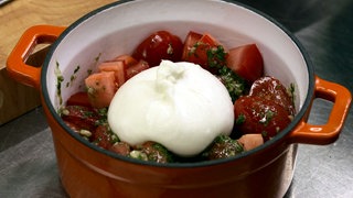 Grillgemüse mit Burrata - brutzelt im gusseisernen Topf auf dem Grill.