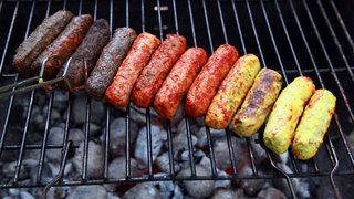 Mehrere vegane Bratwürste nebeneinander auf einem Grill