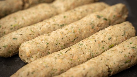 Noch rohe vegane Bratwürste in einer Pfanne