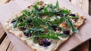 Flammkuchen mit Rucola und Ziegenkäse und roten Früchten