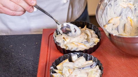 Für die Gemüsequiche Zucchini und Aubergine kleinschneiden und mit Ziegenkäse und Ei zu einem Teig vermengen, der dann in Förmchen gefüllt wird.