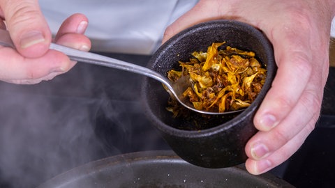 Die Vadouvan-Gewürzmischung wird zu der vegetarischen Hokkaido-Kürbis-Füllung in die Pfanne gegeben.