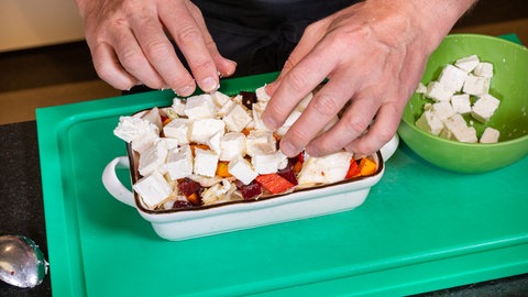 Auf das Gemüse in einer Auflaufform wird der Fetakäse gelegt.