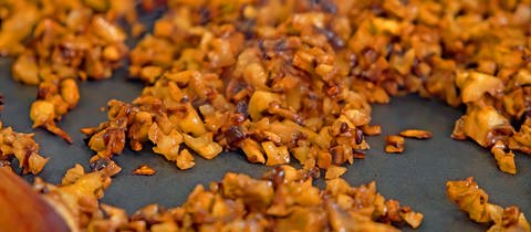 In einer Pfanne sind kleingehackte Pilze und Walnüsse, aus denen veganes Hack gemacht wird. Eine Alternative zu Fleisch für Bolognese und andere Saucen.