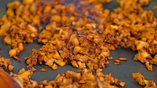 In einer Pfanne sind kleingehackte Pilze und Walnüsse, aus denen veganes Hack gemacht wird. Eine Alternative zu Fleisch für Bolognese und andere Saucen.