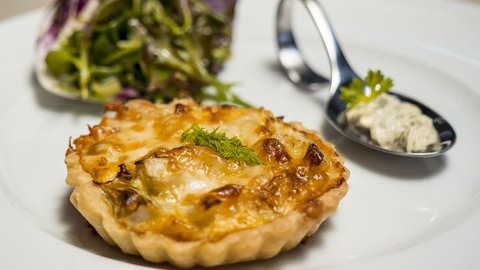 Käse-Fenchel-Quiche und  Salat auf einem Teller