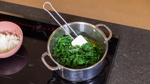 Der Spinat wird in einem Topf angeschwitzt.
