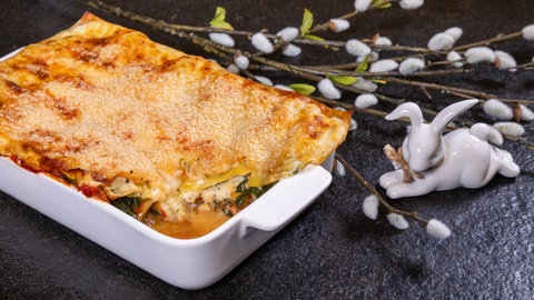Vegetarische Spinat Lasagne mit Tomaten und Sahnesoße in einer Ofenform und mit Käse überbacken.