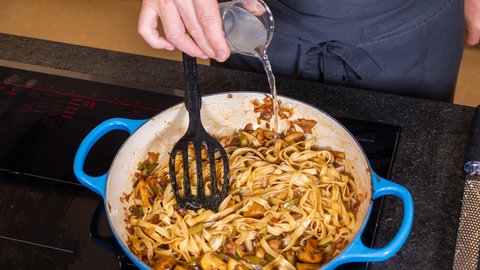 Pasta mit Pilzen: Der Nudelpfanne mit Champignons wird laut Rezept noch Nudelwasser hinzugegeben.