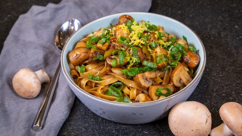 Pasta mit Pilzen: Die nach Rezept frisch zubereitete Nudel-Pilzpfanne mit Champignons ist schön angerichtet in einem Teller.