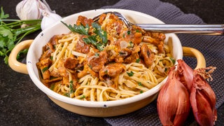 Pfifferlinge mit Nudeln: Cremige Pasta in einem Topf mit Pilzen. Wie im Rezept beschrieben: einfach und schnell zubereitet.