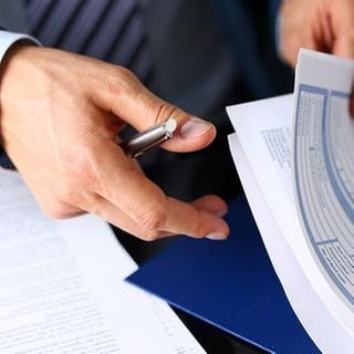 Männlicher Arm in einem Anzug durchsucht Versicherungsunterlagen