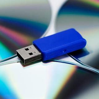 Ein USB-Stick liegt auf spiegelnden Daten-CDs.