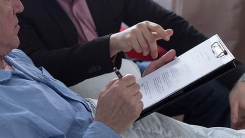 Ein älterer Mann hält ein Dokument in den Händen