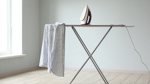 Bügelbrett mit Bügeleisen und Leinenhemd