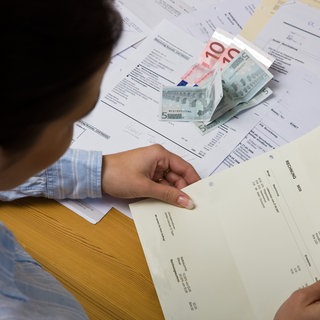 Mann schaut auf Rechnungen - Mahngebühr und Inkasso vermeiden