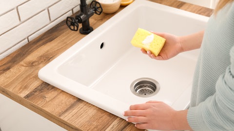 Frau putzt Waschbecken mit Natron