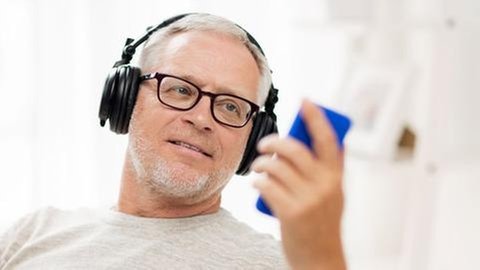 Mann mit Smartphone und Kopfhörern - so hält der Akku des Handys länger