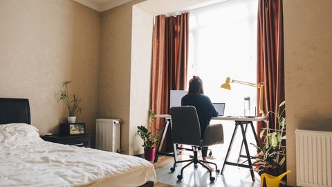 Frau sitzt im Schlafzimmer an einem Schreibtisch