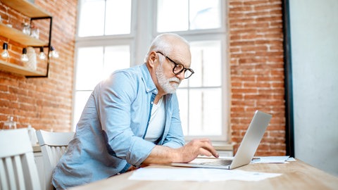 Ältere Mann sitzt am Computer