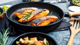 verschiedene Pfannen mit Fisch und Gemüse