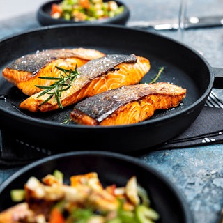 verschiedene Pfannen mit Fisch und Gemüse